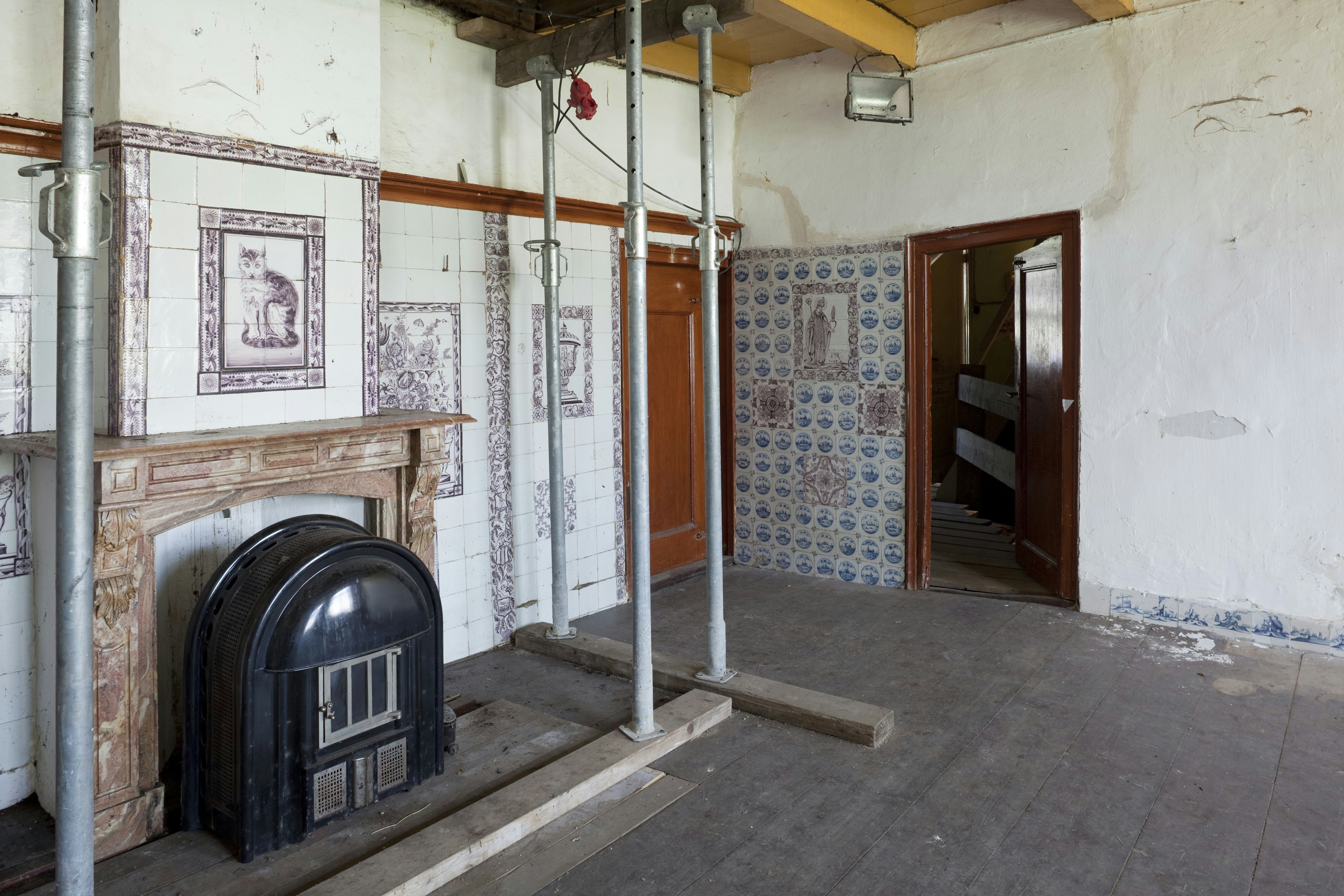 Een kolenkachel onder de schouw in de tegelkamer van boerderij Gagelgat in Soest. Foto uit 2009 van een historisch interieur.